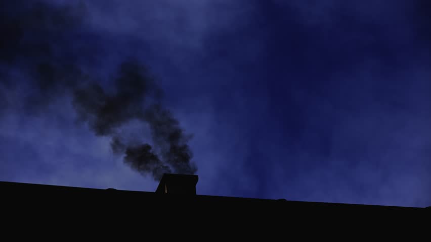 Silhouetted image of smoke drifting from a chimney into the dark sky