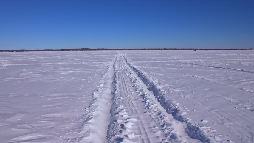 POV ride snowmobile atv or snowdog across the wide frozen lake surface of Simcoe lake in Cook’s Bay, Innisfil, Ontario, Canada. Winter ice fishing season charters for jumbo perch, pike, white fish.
