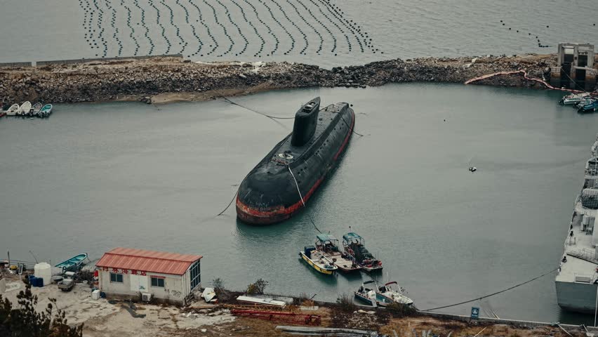 Submarino clase Kilo abandonado junto al mar. Tomas aéreas con dron y planos estáticos que muestran el casco y la torre desde distintos ángulos, con el agua y la costa de fondo. Ideal para documentales, historia naval y contenido industrial.