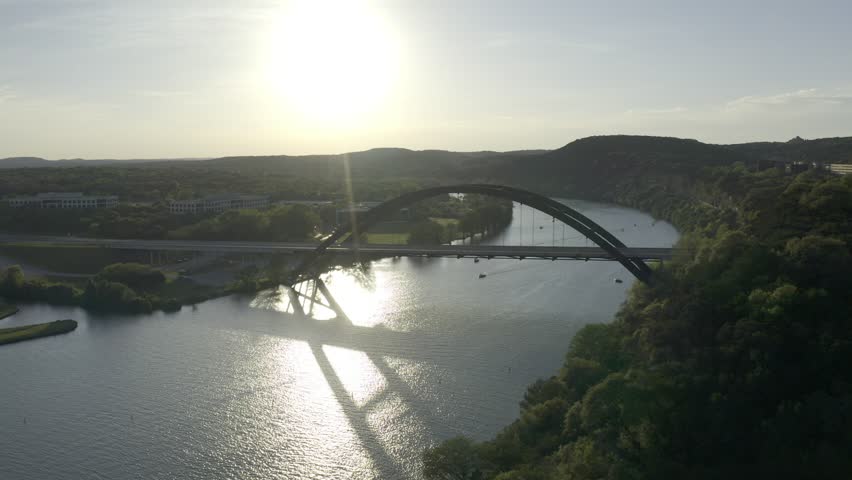 Aerial drone footage of the Pennybacker Bridge, also known as the 360 Bridge, spanning Lake Austin in Austin, Texas. The video shows the iconic arched bridge, surrounding Hill Country landscape, and scenic views frequently used in media coverage of Austin.