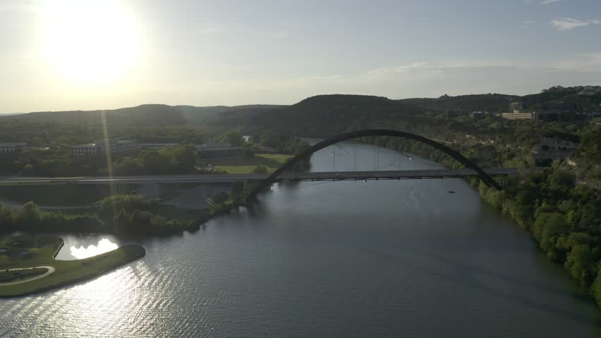 Aerial drone footage of the Pennybacker Bridge, also known as the 360 Bridge, spanning Lake Austin in Austin, Texas. The video shows the iconic arched bridge, surrounding Hill Country landscape, and scenic views frequently used in media coverage of Austin.