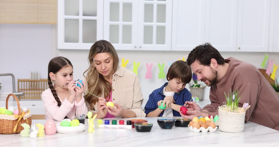 Easter celebration. Family painting eggs at white marble table in kitchen