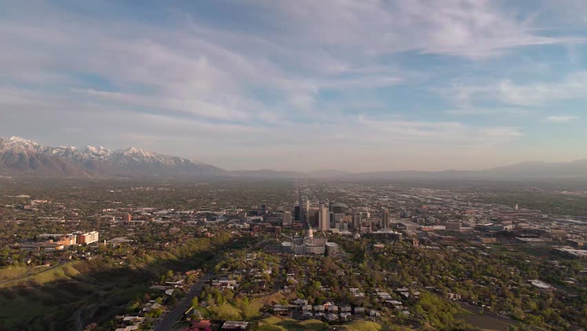 Stunning aerial perspective of Salt Lake City, showcasing lush greenery and towering snow-capped mountains in the backdrop, perfect for travel and nature content.