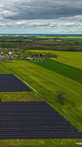Cloud shadows pass over rural settlement and solar fields within vast farmland under layered clouds