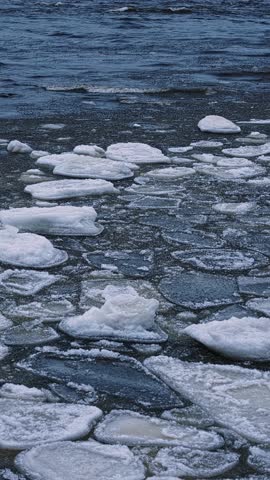 Floating ice sheets thin and separate as lake water regains movement in early spring, vertical static with waves