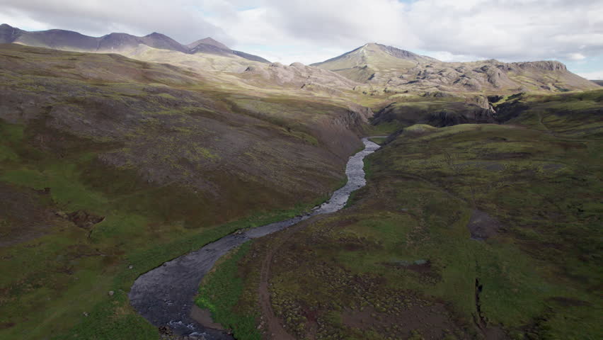 Epic aerial view of a river flowing out of the Icelandic mountains from Trollafoss Waterfall, Iceland