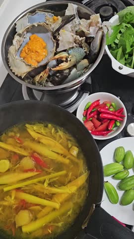 Seafood and vegetables being prepared and cooked in a lively kitchen with boiling broth and fresh ingredients creating a vibrant culinary scene perfect for food and cooking content