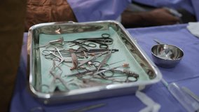 Sterile surgical instruments arranged on a metal tray in an operating room, prepared for a medical procedure on a draped table. - Powered by Shutterstock - Get 15% off with code: PIKWIZARD15