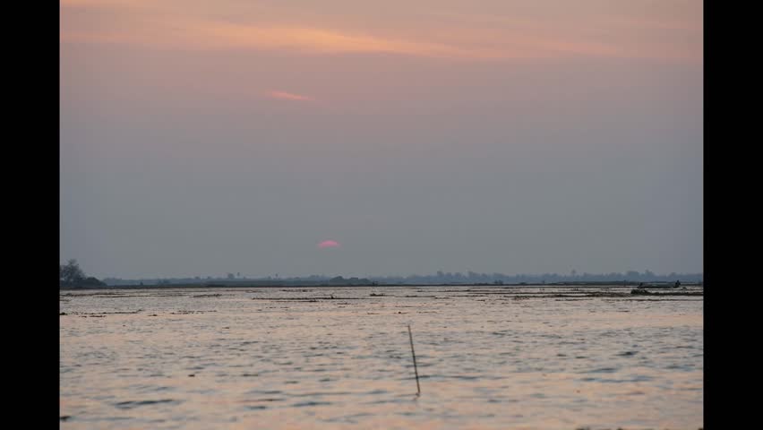 Golden Sunset Over Lake: The sun dips below the horizon, painting the sky with warm hues, casting its glow over a tranquil lake.