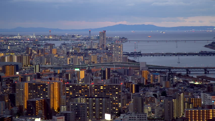 Aerial dusk view looking west from Umeda Sky Building. Featuring the Yodo River flowing toward the Osaka Port and bay area during a vibrant winter sunset. Filmed in Osaka, Japan