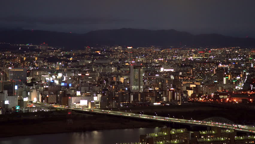 Aerial night view looking north from Umeda Sky Building. Featuring the illuminated Hankyu Railway lines crossing the Yodo River toward the Juso and Shin-Osaka districts. Filmed in Osaka, Japan