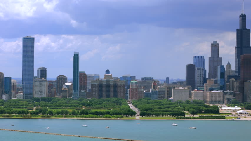 Chicago Illinois skyline seen from above with modern skyscrapers, green park shoreline and calm Lake Michigan water, summer daylight, urban cityscape with iconic downtown architecture.