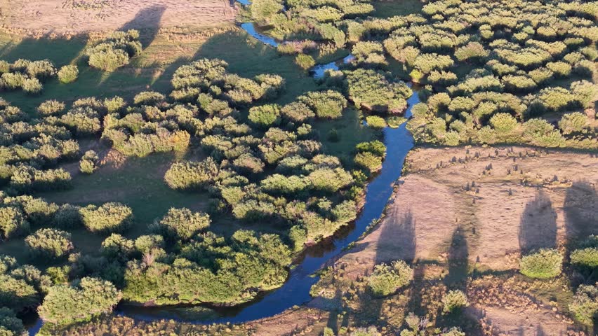 Aerial footage of rural Idaho farmland around the Snake River, showing green trees lining the water and open fields.