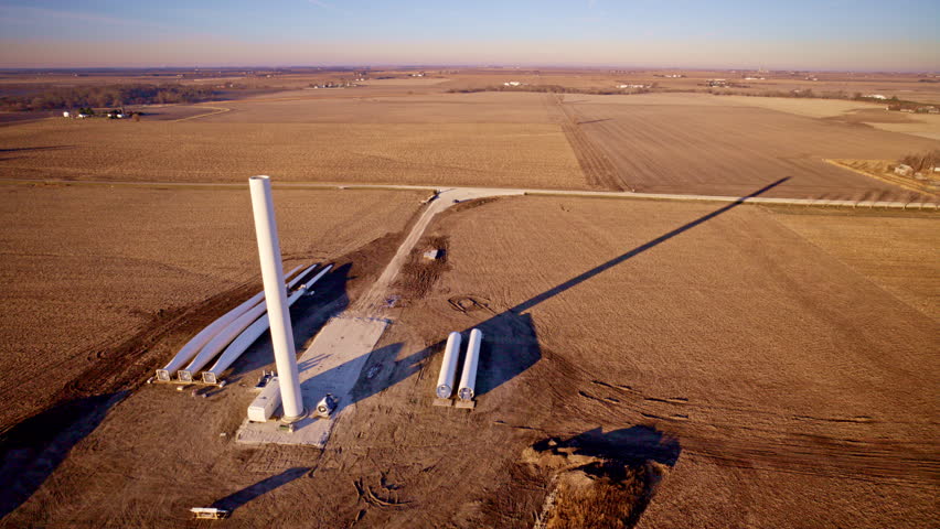 Drone view of industrial cranes assembling wind turbines in rural Illinois
