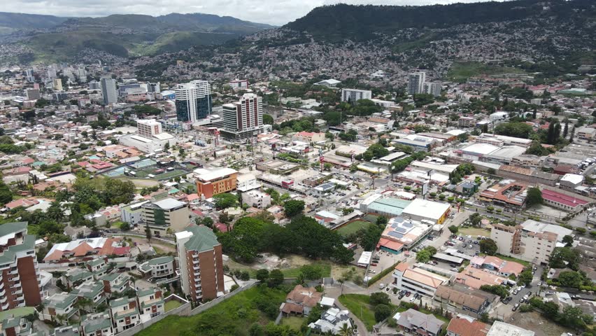 Tegucigalpa, Honduras aerial drone footage showing dense urban districts, residential neighborhoods, commercial zones and road network across the capital city within surrounding hills.