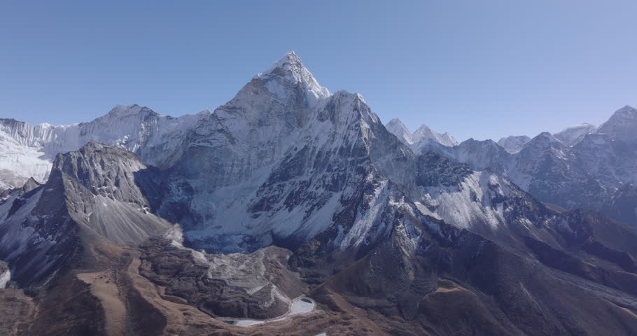 Aerial gliding drone shot of Ama Dablam in Nepal’s Everest region, showcasing the Himalayan mountain view. Reduced snow cover on surrounding peaks highlights visible environmental change at high altit