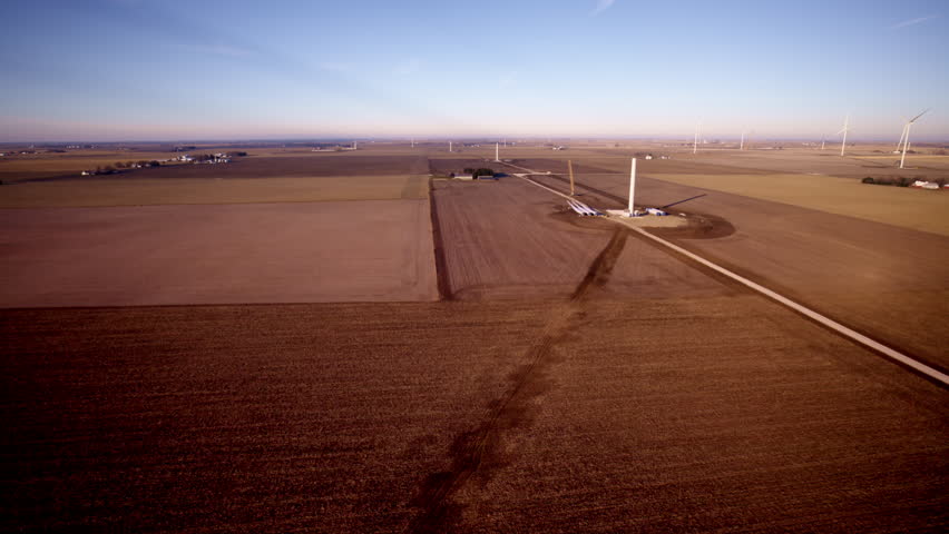 Cinematic drone shot capturing modern wind turbines under construction in the Midwest