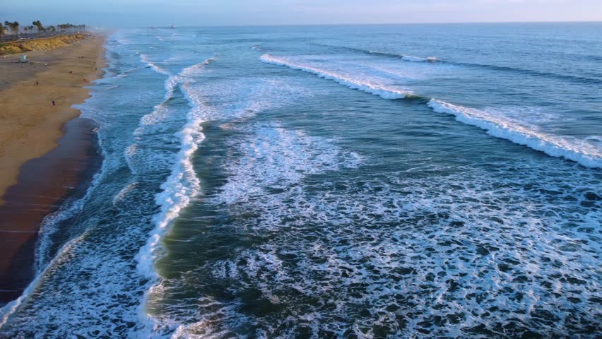 Calm Ocean waves rolling into shore in Huntington Beach, Orange County, California. PCH Pacific Coast Highway looking towards HB Pier