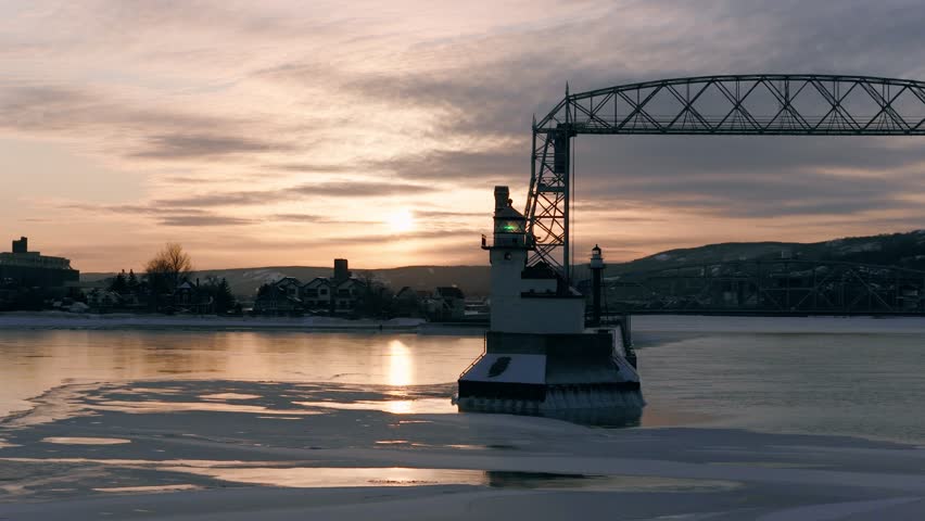 Duluth North Pier Lighthouse and Aerial Lift Bridge at dawn with thick winter frost smoke swirling over the icy waters of the Duluth Ship Canal.