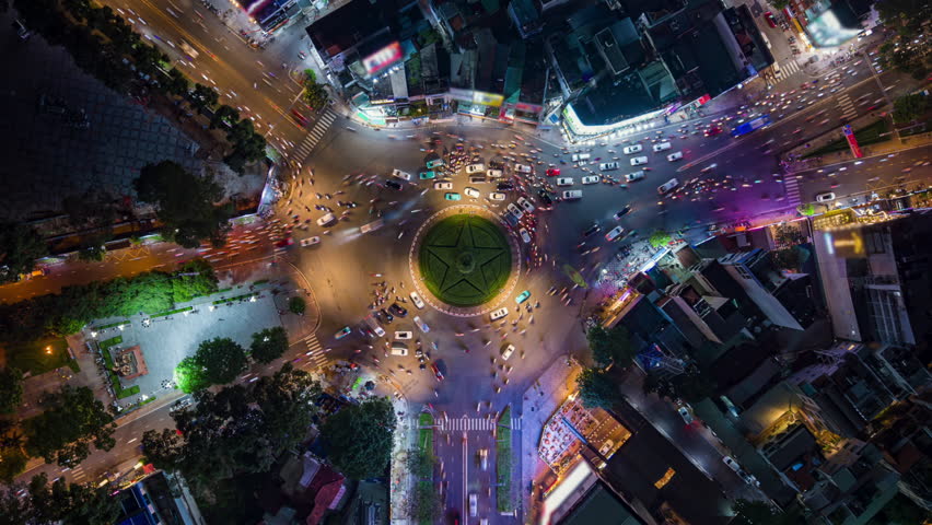 Top-down aerial timelapse of intense traffic at night in Ho Chi Minh City. Glowing city lights and fast-moving vehicles show urban energy, congestion, and modern life in Vietnam.