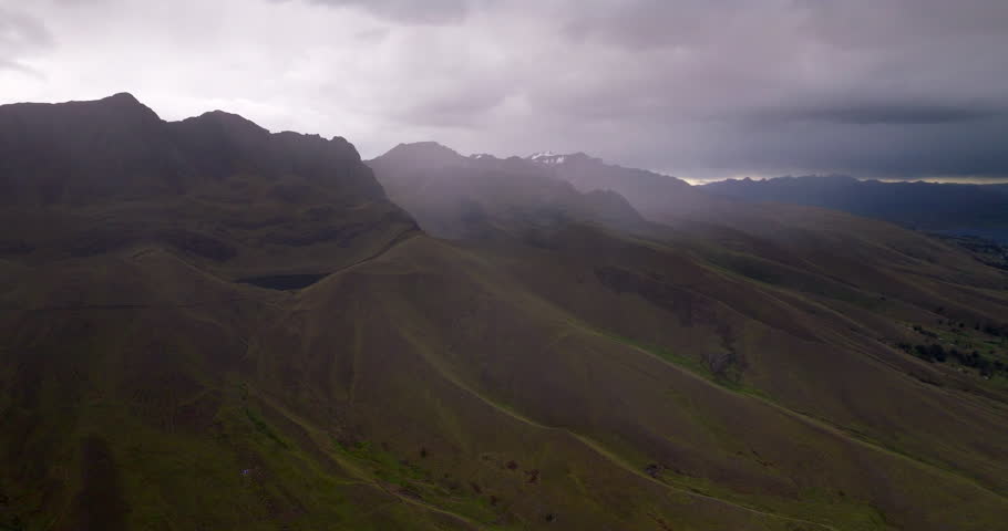 Misty Andean mountains and layered ridges under dramatic clouds near Laguna Langui Peru, aerial medium backdrop