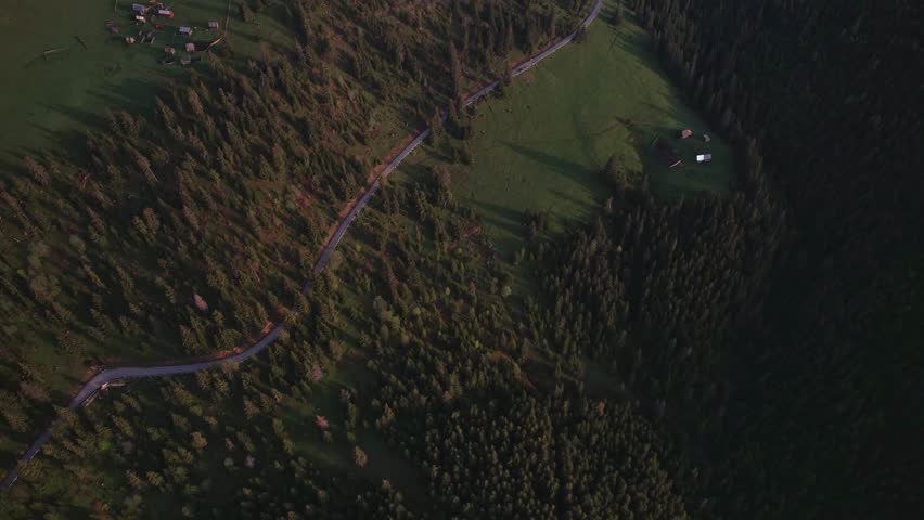 Rural countryside of Romania in the remote mountains seen from above with houses and shepherd cottages during spring