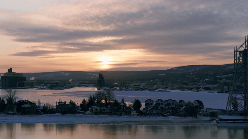 erial sunset view of Park Point and the Duluth shipping harbor in winter. Golden light reflects off ice and sea smoke over the Minnesota Slip and bay.