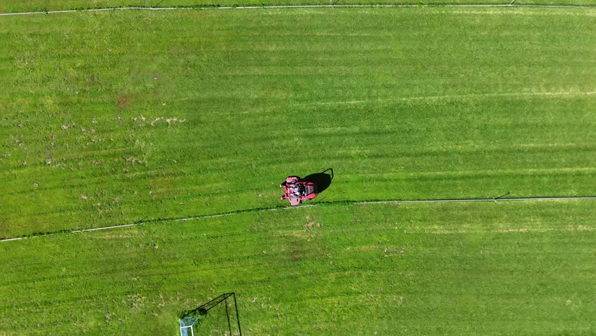 Aerial Shot of Red Riding Mower Grooming Soccer Field Grass