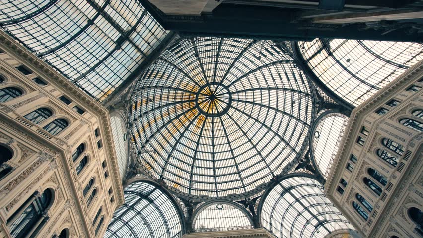 Low angle view looking up at the intricate steel and glass dome ceiling of the historic Galleria Umberto I shopping arcade in Naples, Italy.