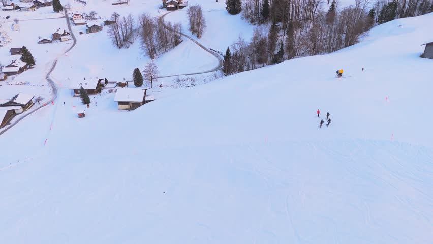 Ski Piste and Skiers in Grindelwald Town in Winter. Wooden Chalets. Swiss Alps. Switzerland. Aerial View. Orbiting
