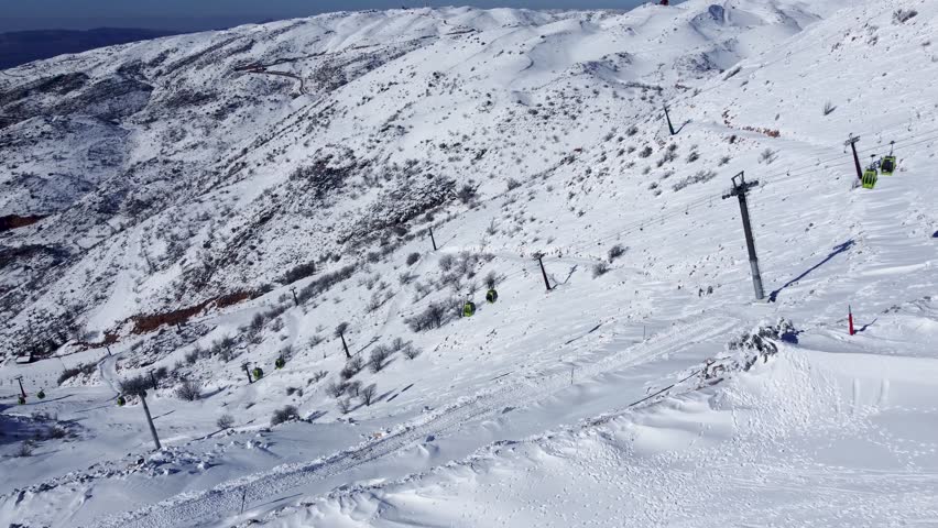 Impressive aerial view showcasing the snow-draped slopes of Mount Hermon, featuring ski gondolas and winding trails in bright winter light.