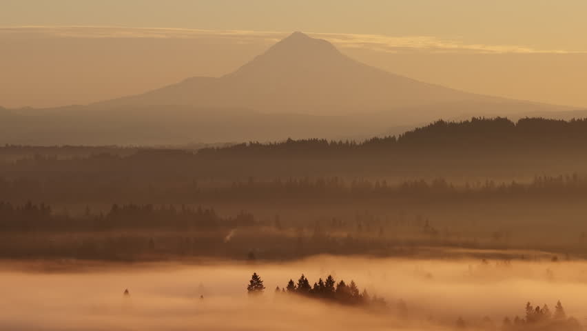 The scenic Mount Hood rises in the distance from the forested landscape of northern Oregon. This iconic Pacific Northwest mountain is part of the Cascade Mountain Range.