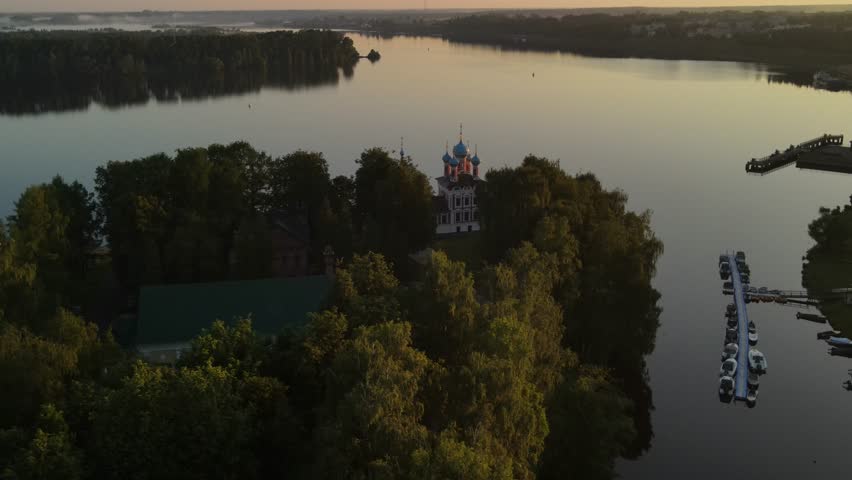 Aerial drone shot of the Church of Demetrius on the Blood in the Uglich Kremlin. Flight over the red facade and onion domes against the flow of the Volga River. 
