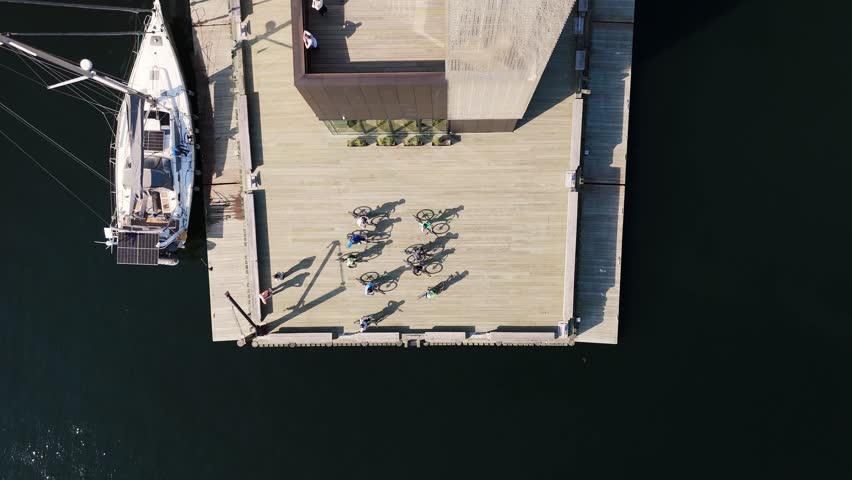 Top View Group of tourists explore Halifax waterfront by bike, passing landmarks and ocean views. Downtown streets and sparkling sea form a scenic backdrop in Nova Scotia, Canada.