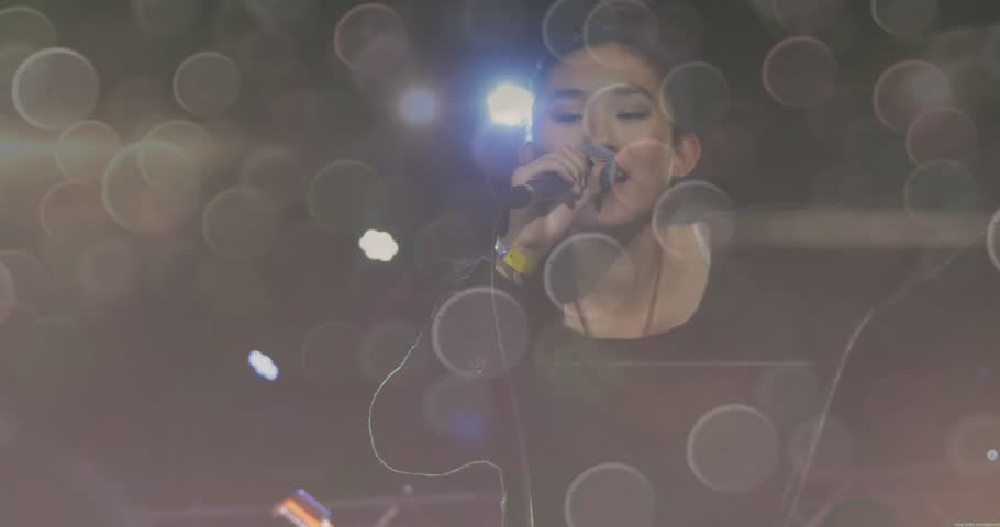 Female singer performing music onstage, with animated lens flares and bokeh orbs guiding focus. Performance, vocalist, spotlight, abstract, entertainment, vibrant, energy