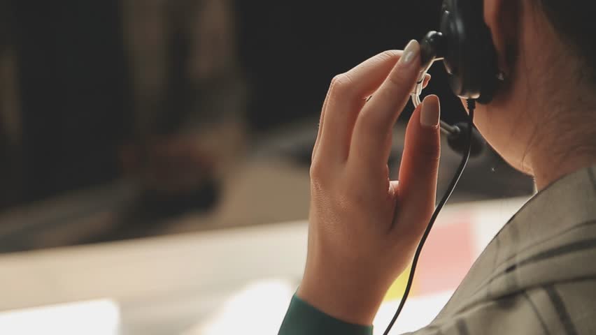 Young woman wearing headset talking, computer in background, office call center environment, close-up footage.