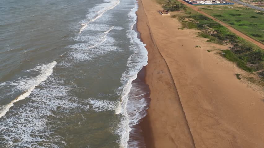 drone fly above ocean waves crashing on wild golden sand beach in west africa Benin Ouidah
