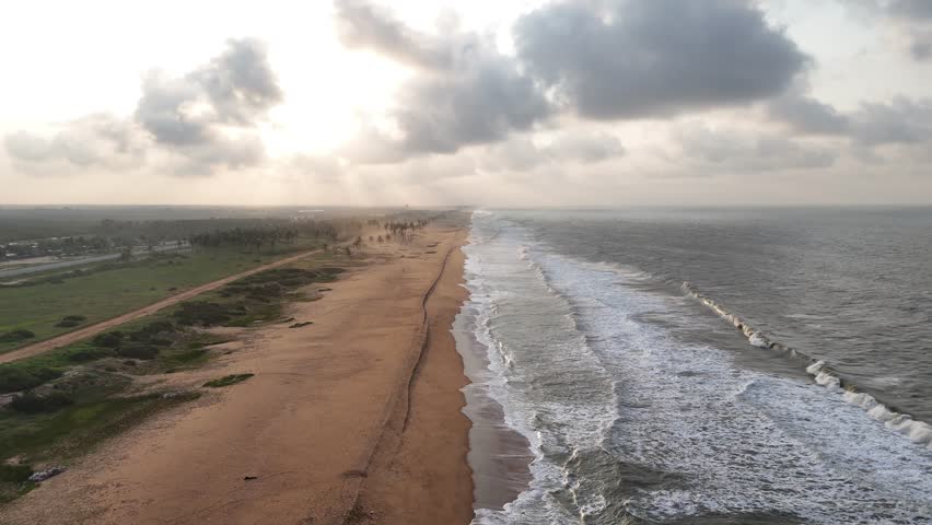 Cinematic high-angle perspective of the vast West African shoreline in Ouidah, Benin showing the contrast between the golden sand and the deep blue ocean