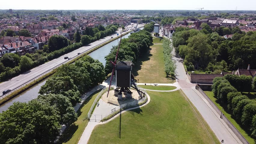 Aerial view of old windmills, historic architecture, and a canal in Brugges, Belgium. Travel stock footage of Europe in summertime