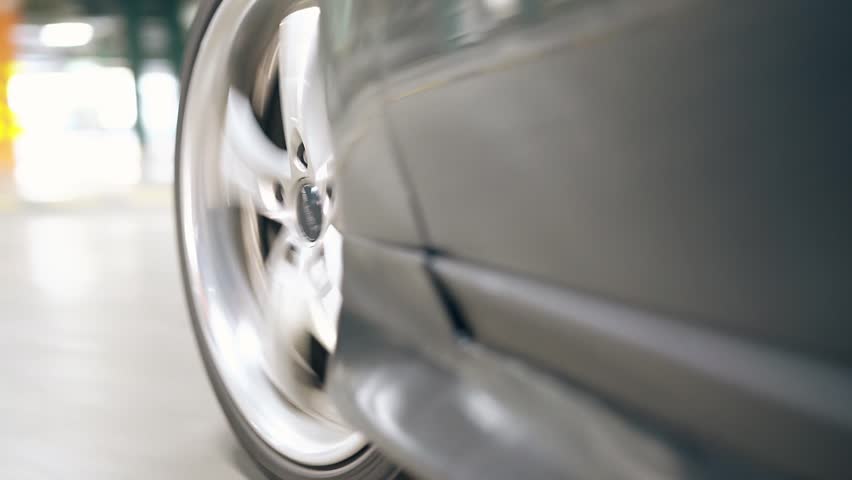 Close-up of a car wheel in motion, showing speed, tire rotation, automotive dynamics, transportation, and road travel in a dynamic, high-energy shot.