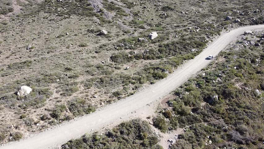 A car drive on a dirt road through a dry, rocky landscape. Travel to arid Argentina. Explore. Calm, scenic. Great for travel ads