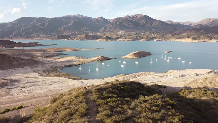 Aerial view shows sailboats on blue mountain lake in Mendoza, Argentina. Evokes peace and beauty. Great for travel, nature films