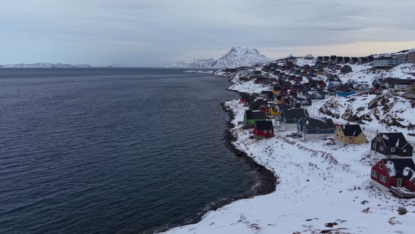 Cinematic shot of the iconic multicolored wooden houses in Nuuk, Greenland. A perfect representation of Arctic living along the rocky coastline.