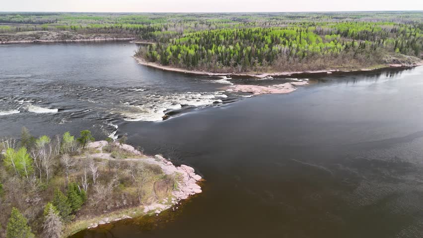 Aerial drone footage of Sturgeon Falls in Whiteshell Provincial Park, Manitoba, Canada, during autumn. Water cascades through a forested landscape surrounded by colorful fall foliage under natural daylight.