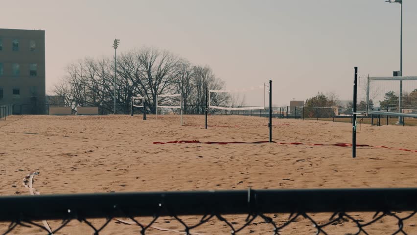 Steady handheld shot of empty sand volleyball courts at an outdoor park.