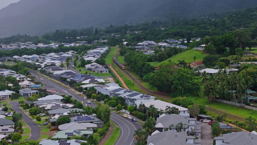 Freight train traveling through tropical Cairns suburb aerial drone view Far North Queensland Australia
