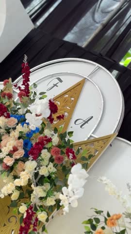 Elegant floral arrangement featuring roses and orchids heavily adorns a large decorative clock structure used for a special event staging.