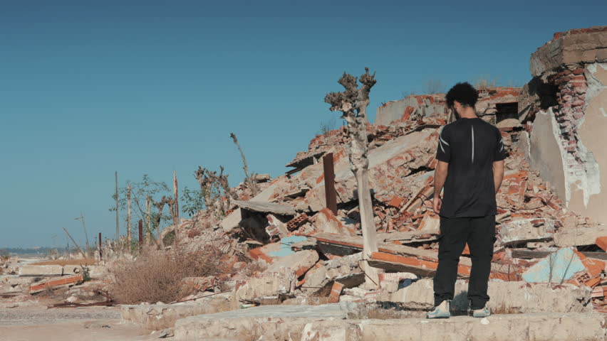 Man standing in destroyed urban ruins holding his head in despair, symbolizing loss, trauma, and the human impact of war.