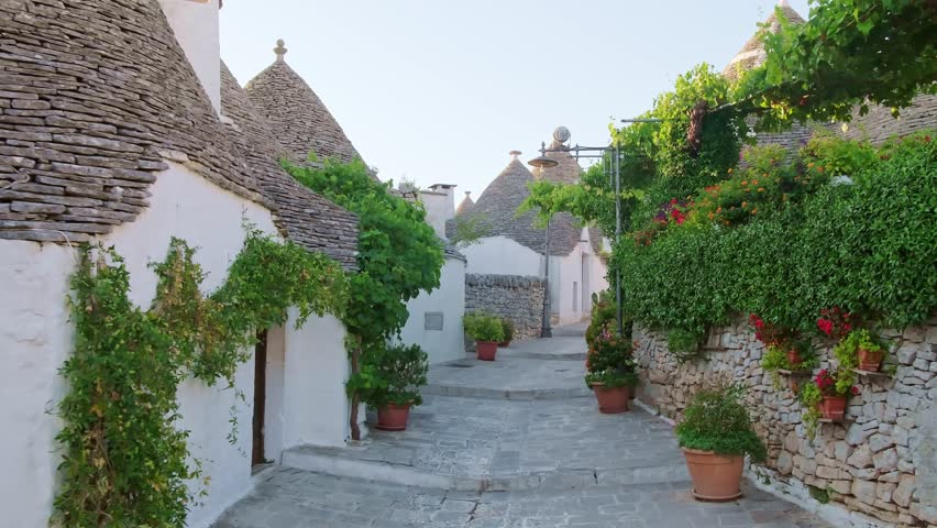 Alberobello, Italy. Walking past whitewashed Trulli houses in Puglia. These unique UNESCO World Heritage dwellings feature iconic conical limestone roofs in a fairy tale setting. Steadicam footage