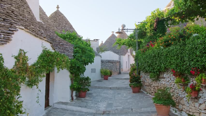 Alberobello, Italy. Walking past whitewashed Trulli houses in Puglia. These unique UNESCO World Heritage dwellings feature iconic conical limestone roofs in a fairy tale setting. Steadicam footage